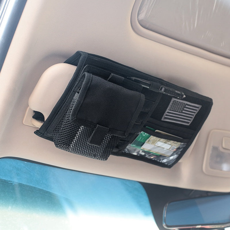 Black sun visor organizer installed on a car visor, holding a pen and cards in its clear pocket