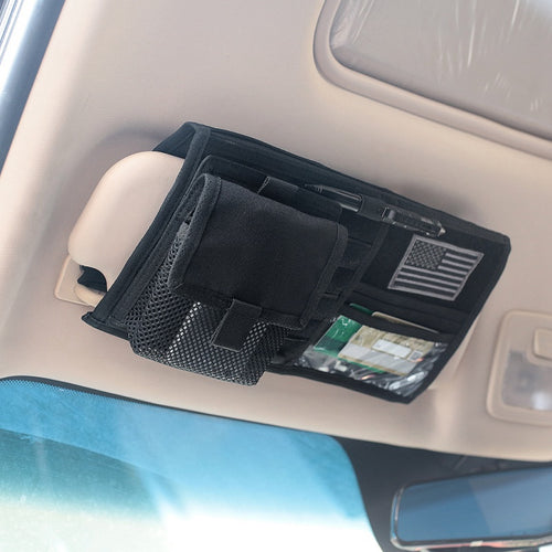 Black sun visor organizer installed on a car visor, holding a pen and cards in its clear pocket