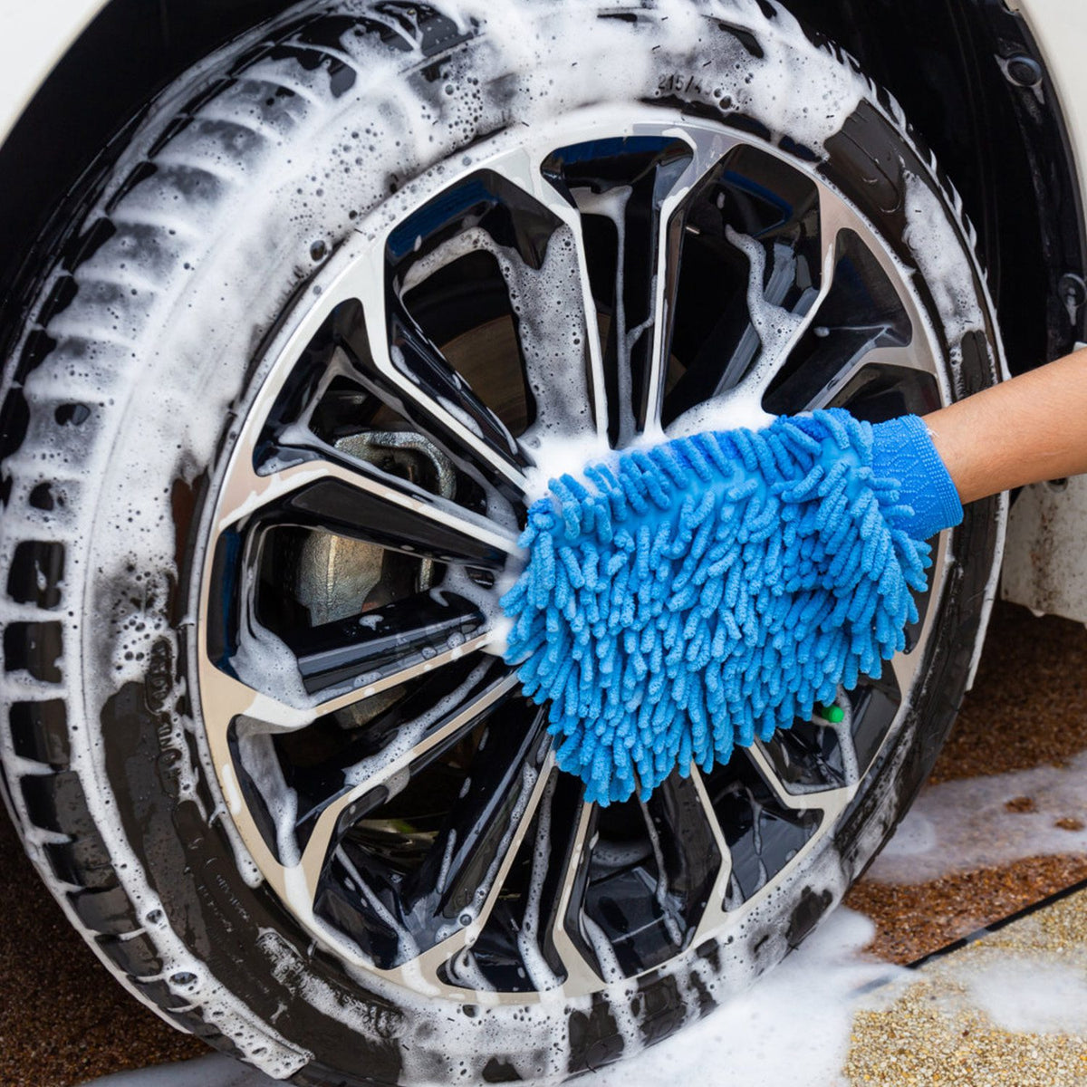 Blue microfiber wash mitt washing a soapy car wheel