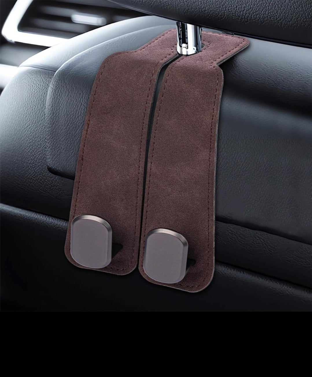 Brown suede-look leather car purse hook with double metal hooks mounted on a headrest post, shown on a black leather seat back