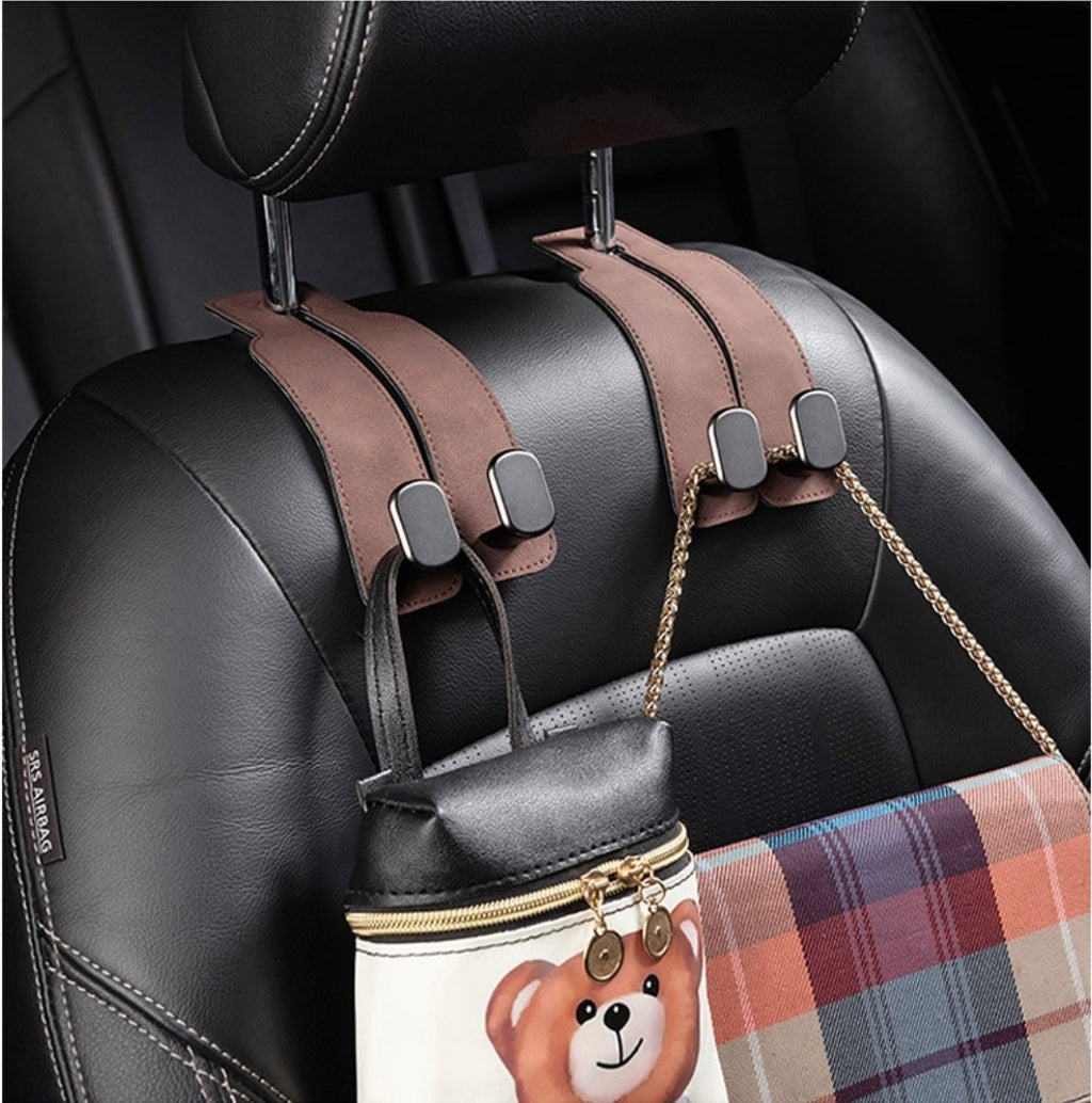 Two brown suede-look leather purse hooks mounted on a car seat back holding handbags by their straps and chains