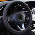 Black fiber leather steering wheel cover with red stitching installed on a car steering wheel
